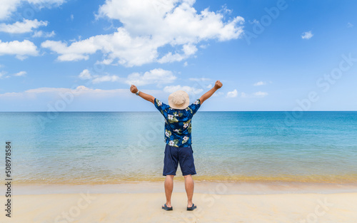 Young Asian man raise his hands up by the sea, vacation time,