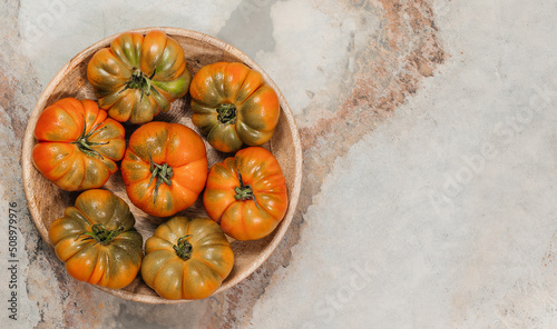 A group of Costoluto big tomatoes on a wooden plate, space for text