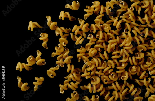 Uncooked durum pasta, funghetti pile isolated on black, top view