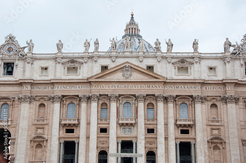 Madernos facade exterior with colums and statues standing on top of Saint Peters Basilica in Vatican