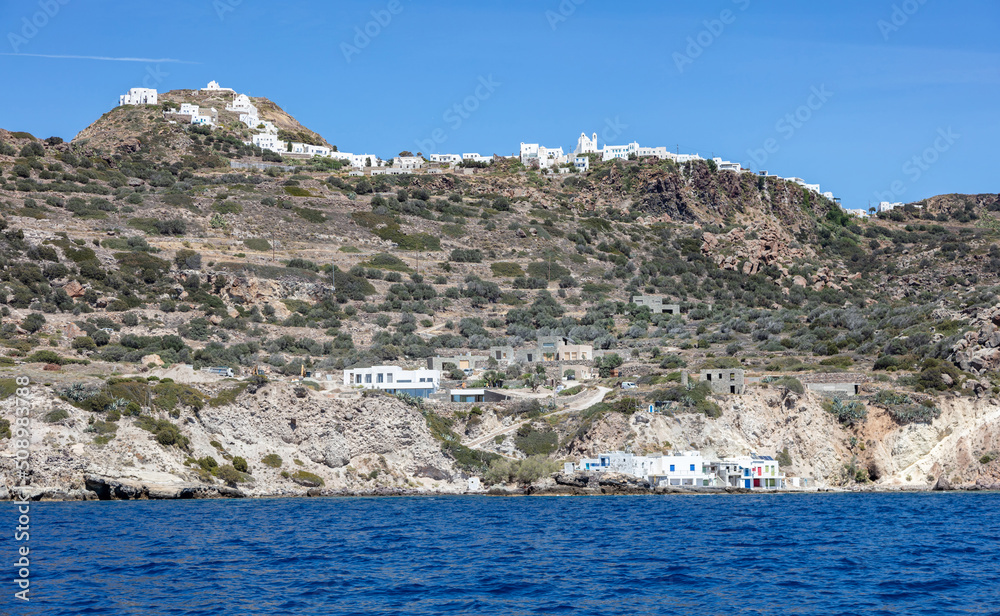 Cyclades Greece. Milos island, traditional building on the coast and town uphill, view from the sea