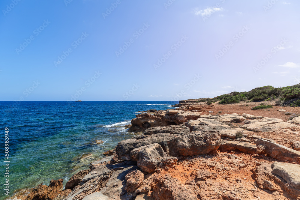 Very gently sloping low coast of Ibiza island and transparent turquoise sea, Balearic Islands, Spain Very gently sloping low coast of Ibiza island and transparent turquoise sea, Balearic Islands, Spain