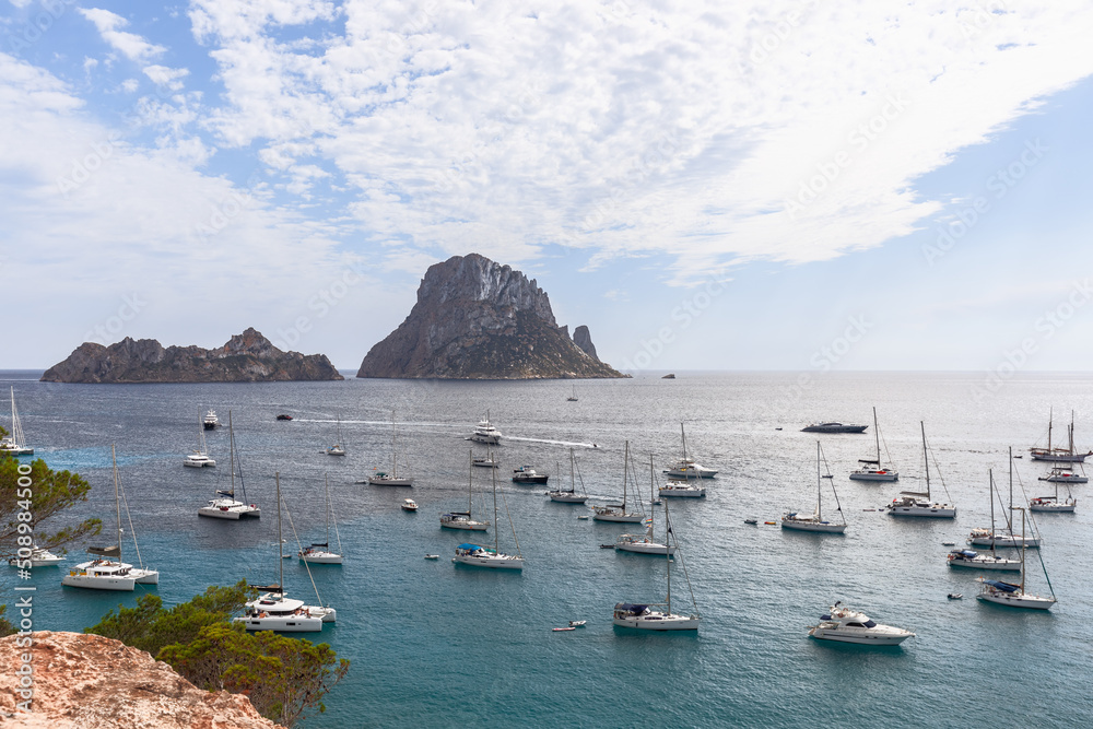 Mediterranean Sea, white catamarans and yachts of different sizes and types are anchored in bay Cola d'Hort. Ibiza, Balearic Islands, Spain