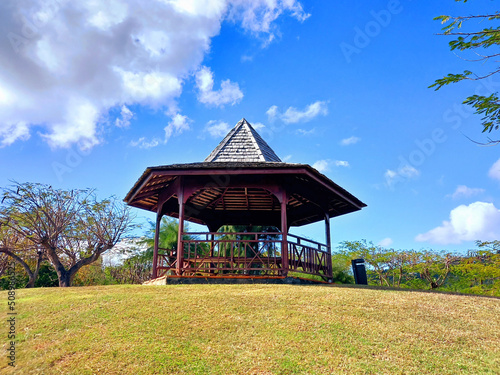 Wooden pergola in French West Indies garden under tropical blue sky. Decorative furniture for parks. Caribbean Architecture and Construction. © Su Nitram