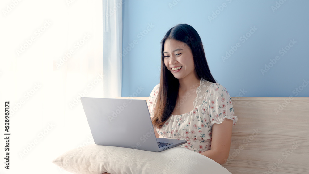 Pretty Asian girl, wearing a floral shirt, sitting and thinking about what to order online, with a serious expression, on table are three credit cards, online shopping. Pretty Asian girl, wearing a floral shirt, sitting and thinking about what to order online, with a serious expression, on table are three credit cards, online shopping.