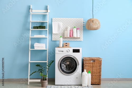 Interior of laundry with modern washer near color wall photo