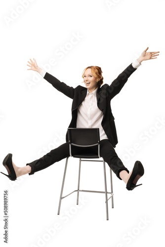 Delighted young businesswoman sitting on chair with hands and legs apart