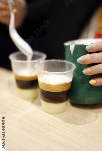 elaboración de café bombón barraquito con licor y mano con manicura de camarera photo
