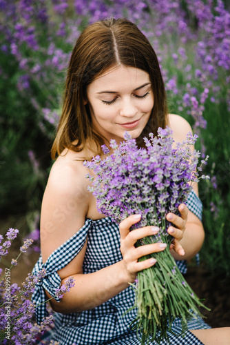 Beautiful girl hold bouquet purple lavender flowers in field. Female collect lavender. Woman in the lavender field. Enjoy the floral glade  summer. Down view. Close up