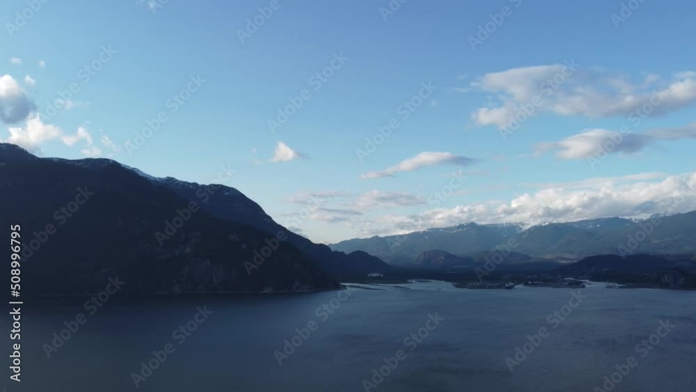 Fly over azure lake in the evening surrounded by mountains and blue sky Fly over azure lake in the evening surrounded by mountains and blue sky