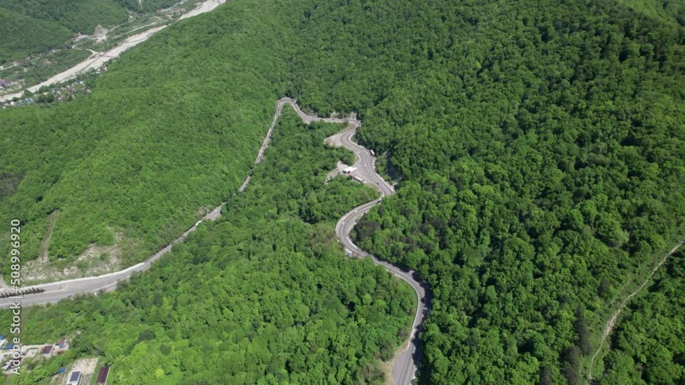 Aerial view of winding road from the high mountain pass. Great road trip trough the dense woods. Birds eye view. Aerial view of winding road from the high mountain pass. Great road trip trough the dense woods. Birds eye view.