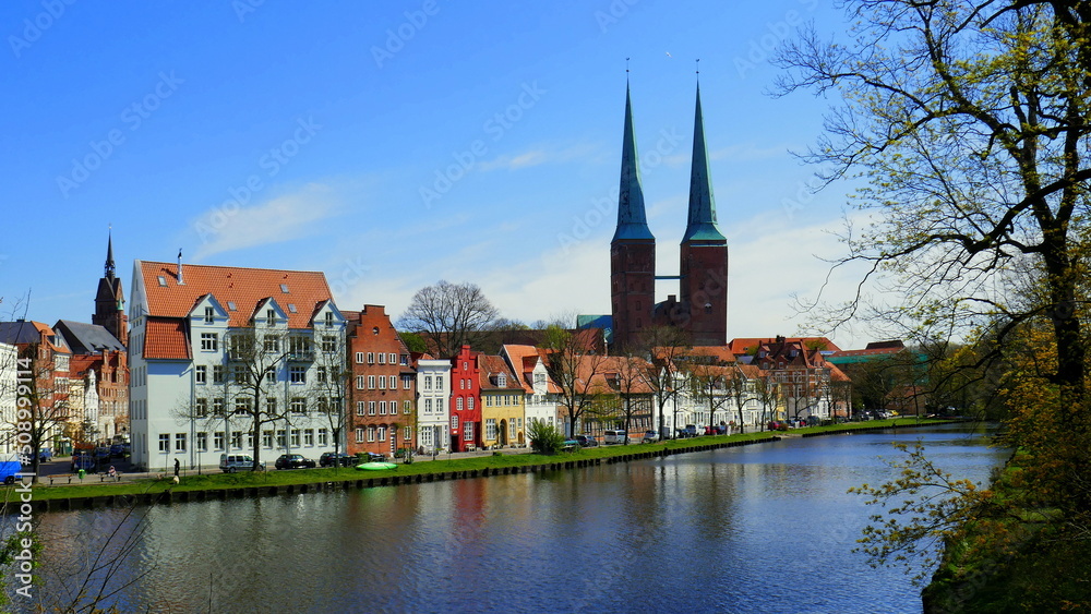 malerische historische Häuser entlang der Trave in Lübeck  und Türme des Domes unter blauem Himmel