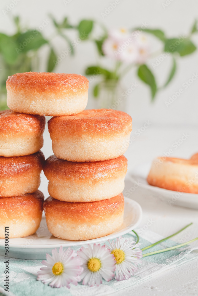 Many delicious golden donuts on a table with mint and daisy. Many delicious golden donuts on a table with mint and daisy.