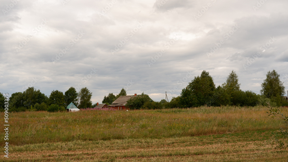 Beautiful rustic summer landscape with old wooden houses and hay in the field Beautiful rustic summer landscape with old wooden houses and hay in the field