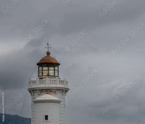 WHITE AND YELLOW FISHING PORT LIGHTHOUSE WITH WINDOWS ON A CLOUDY SPRING DAY