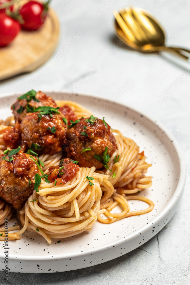 Meatballs served over italian spaghetti pasta with tomato sauce on a light background. Italian food. vertical image. top view. place for text Meatballs served over italian spaghetti pasta with tomato sauce on a light background. Italian food. vertical image. top view. place for text