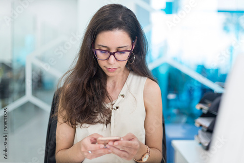 Young woman checking messages on the cell phone at work