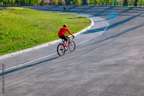A cyclist with red jerseys on the cycle-racing track for training.