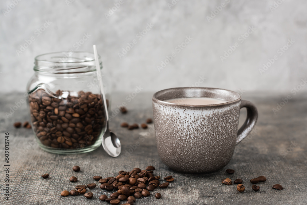 Latte in a ceramic cup and jar with coffee beans on the table. Time for a break and relaxation Latte in a ceramic cup and jar with coffee beans on the table. Time for a break and relaxation