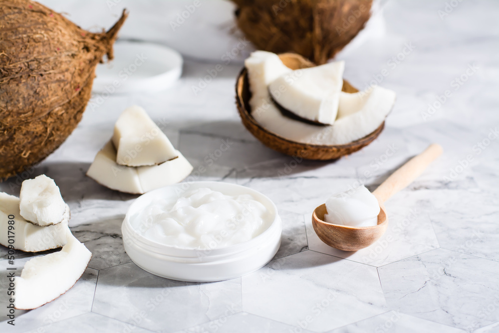 Fresh coconut oil in a jar and spoon and pieces of coconut on the table. Natural cosmetic Fresh coconut oil in a jar and spoon and pieces of coconut on the table. Natural cosmetic