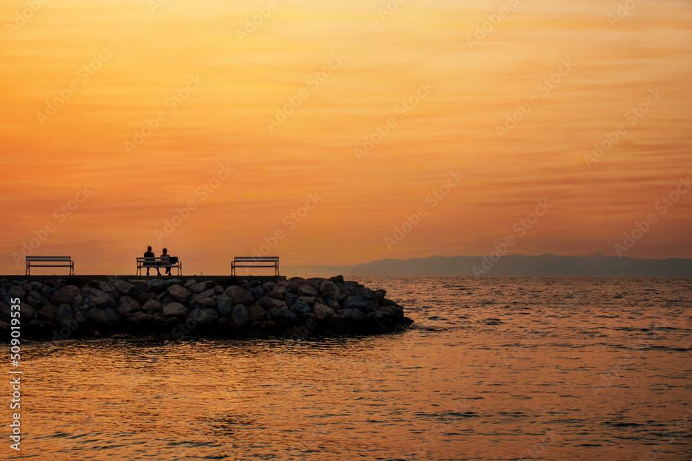 couple relaxing and watching the sea sunset