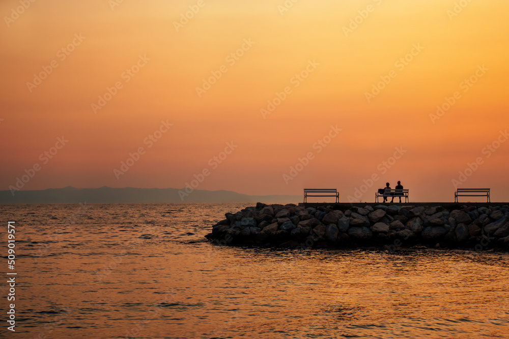 couple relaxing and watching the sea sunset