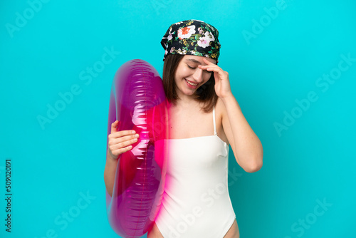 Young Ukrainian woman holding air mattress isolated on blue background laughing