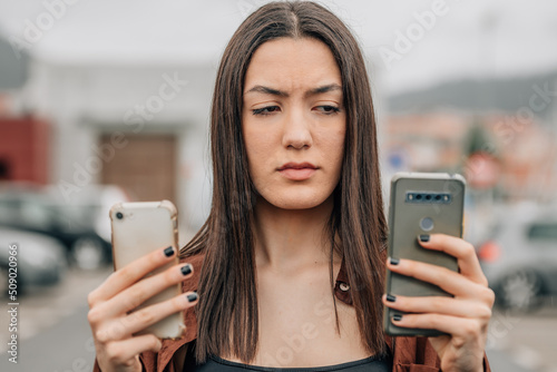 indecisive or distrustful girl looking at mobile or cell phones photo