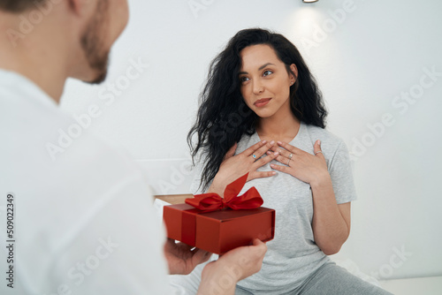Loving male giving present to life companion in bedroom