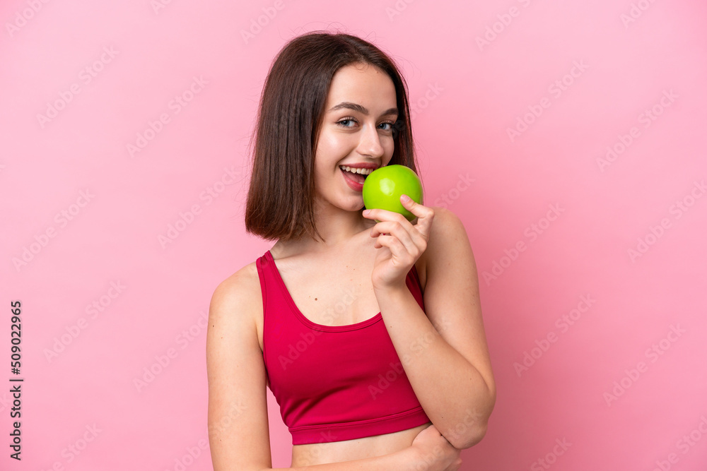 Young Ukrainian woman isolated on pink background eating an apple Young Ukrainian woman isolated on pink background eating an apple