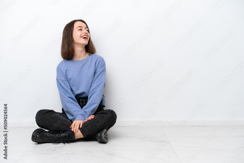 Young Ukrainian woman sitting on the floor isolated on white background laughing in lateral position Young Ukrainian woman sitting on the floor isolated on white background laughing in lateral position
