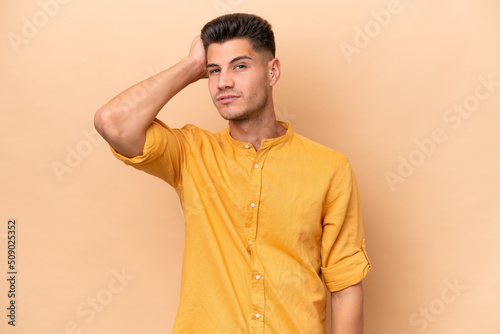 Young caucasian man isolated on beige background with an expression of frustration and not understanding © luismolinero