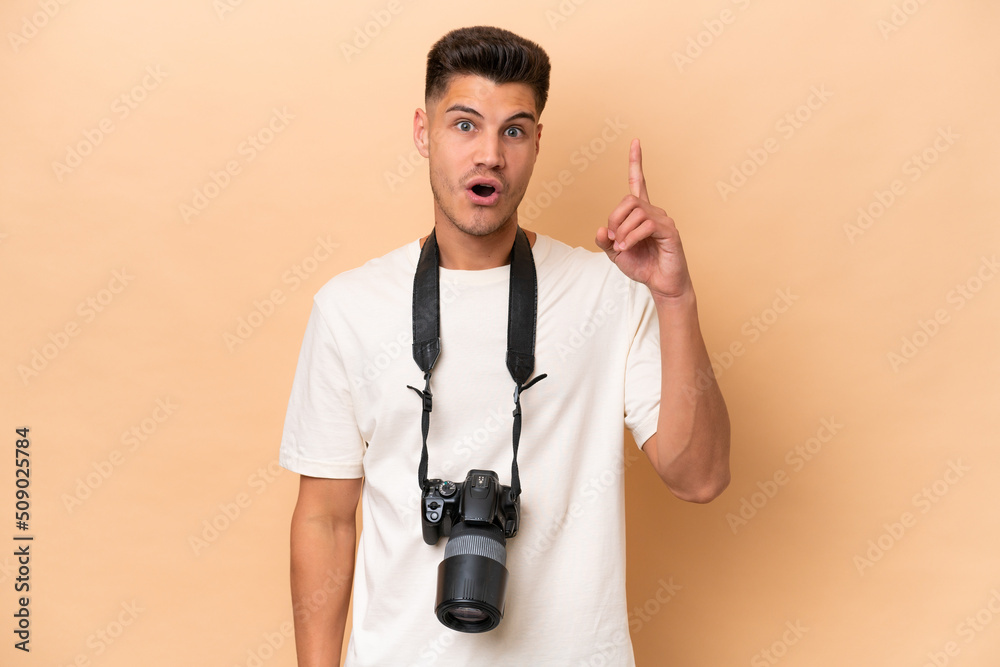 Young photographer caucasian man isolated on beige background thinking an idea pointing the finger up Young photographer caucasian man isolated on beige background thinking an idea pointing the finger up
