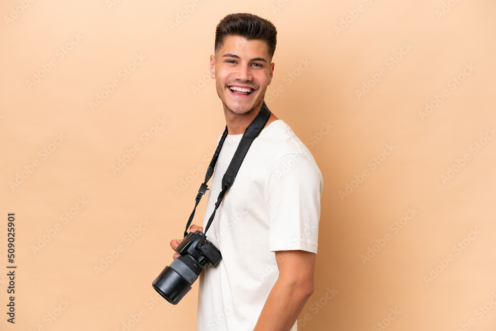 Young photographer caucasian man isolated on beige background with arms crossed and looking forward Young photographer caucasian man isolated on beige background with arms crossed and looking forward