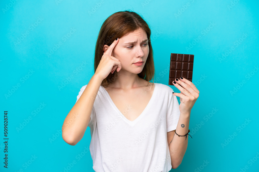 Young English woman with chocolat isolated on blue background having doubts and thinking Young English woman with chocolat isolated on blue background having doubts and thinking