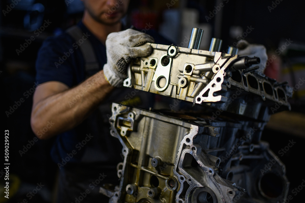 Partial view of repairman in gloves working with damaged car engine in garage Partial view of repairman in gloves working with damaged car engine in garage