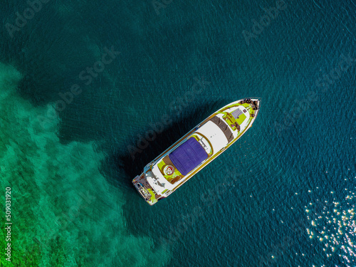 Aerial drone top down ultra wide photo of luxury yacht anchored in tropical exotic island bay with crystal clear turquoise sea.