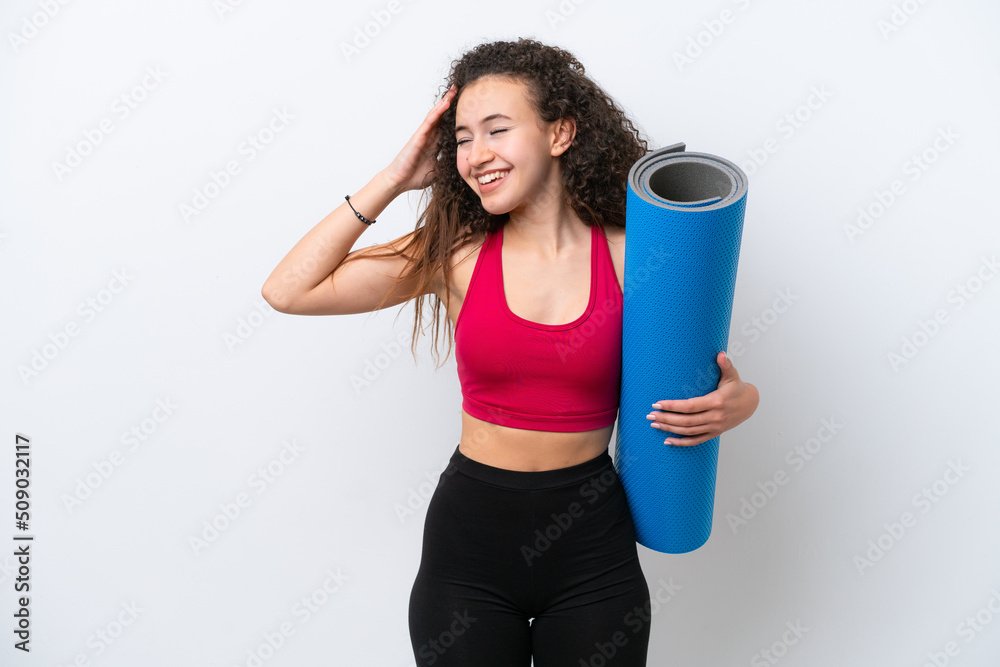 Young sport Arab woman going to yoga classes while holding a mat isolated on white background smiling a lot Young sport Arab woman going to yoga classes while holding a mat isolated on white background smiling a lot