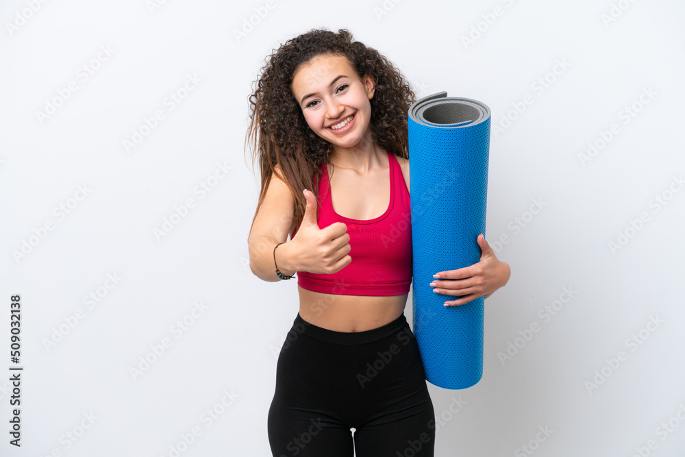 Young sport Arab woman going to yoga classes while holding a mat isolated on white background with thumbs up because something good has happened Young sport Arab woman going to yoga classes while holding a mat isolated on white background with thumbs up because something good has happened