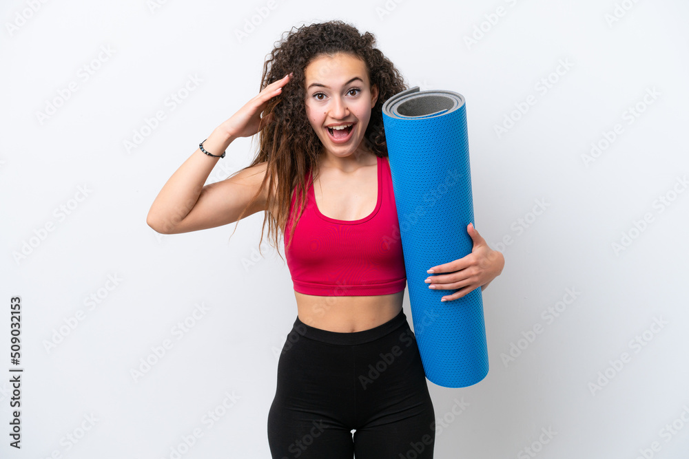 Young sport Arab woman going to yoga classes while holding a mat isolated on white background with surprise expression