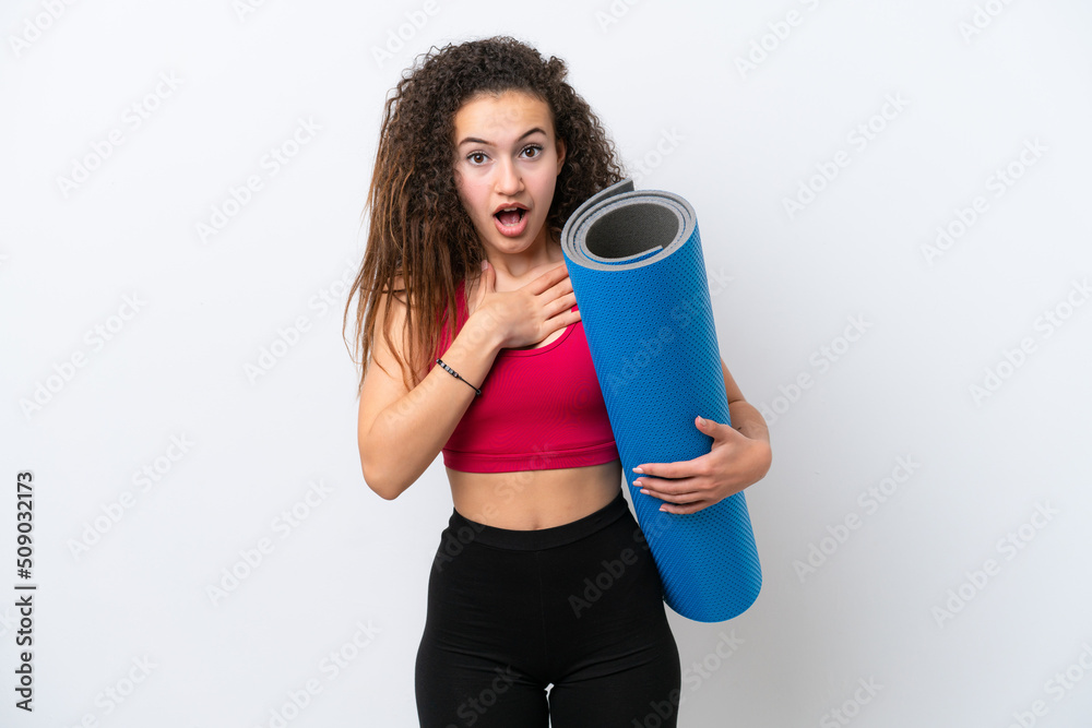 Young sport Arab woman going to yoga classes while holding a mat isolated on white background surprised and shocked while looking right Young sport Arab woman going to yoga classes while holding a mat isolated on white background surprised and shocked while looking right