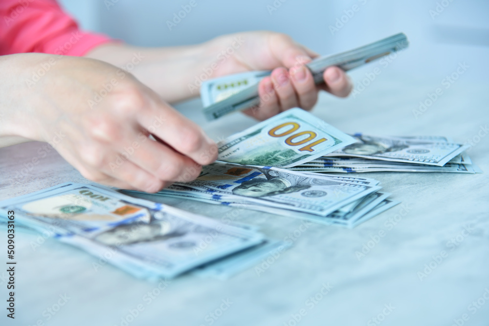 Businesswoman hands arranges dollars into three piles Businesswoman hands arranges dollars into three piles
