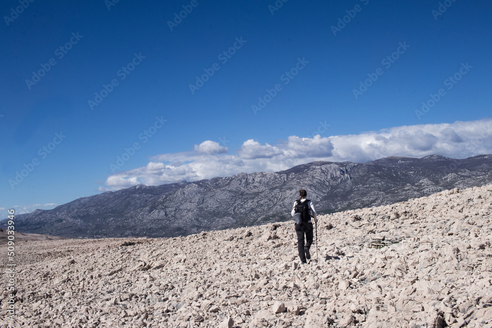 A woman walking in a trail in rocky mountains, deserted place