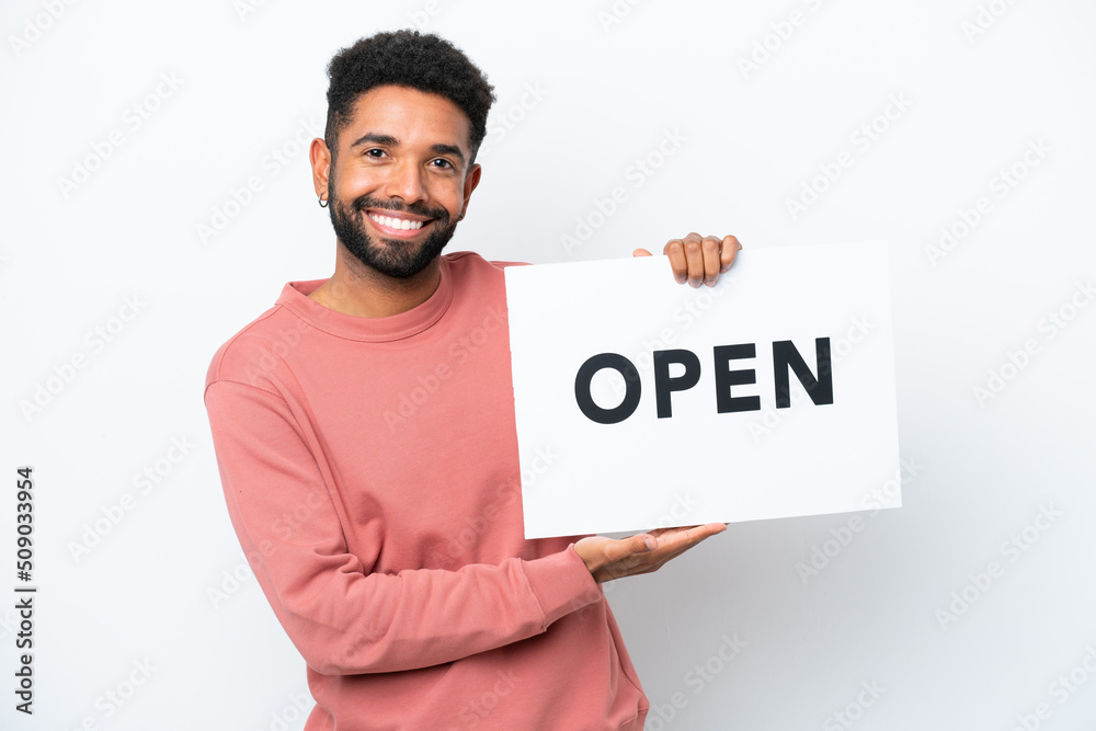 Young Brazilian man isolated on white background holding a placard with text OPEN with happy expression