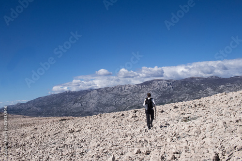 A woman walking in a trail in rocky mountains, deserted place