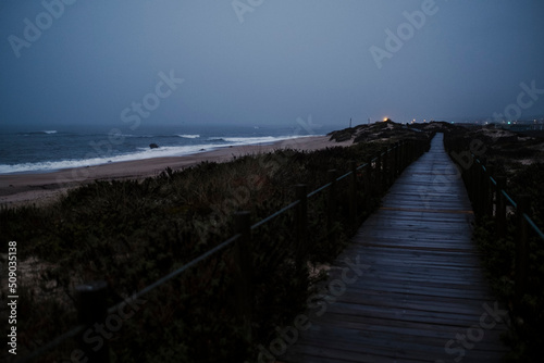 Night wooden trail along the ocean coast in Porto, Portugal.