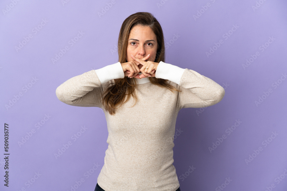 Middle age Brazilian woman isolated on purple background showing a sign of silence gesture Middle age Brazilian woman isolated on purple background showing a sign of silence gesture