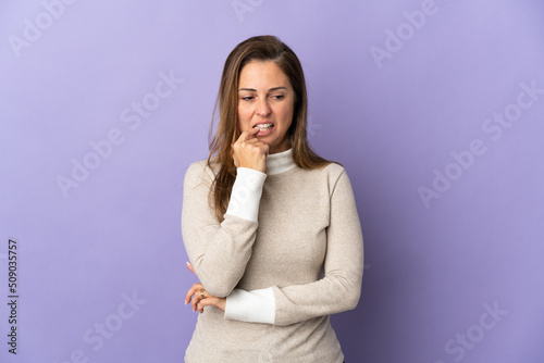Middle age Brazilian woman isolated on purple background nervous and scared