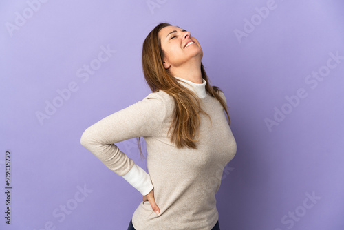 Middle age Brazilian woman isolated on purple background suffering from backache for having made an effort