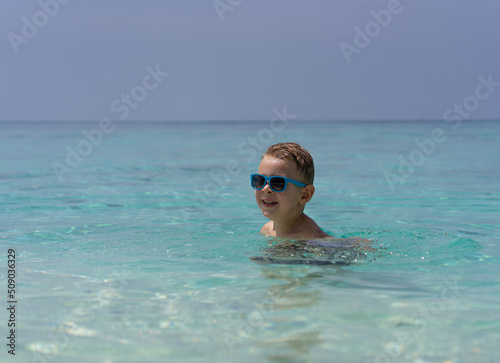 Happy child in sunglasses swims in the Indian Ocean in Maldives © Marina